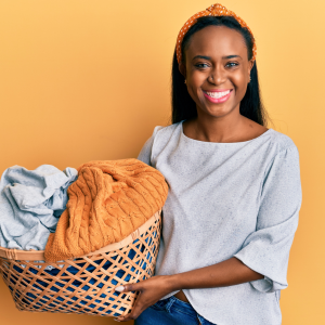 Young Woman Holding Laundry Basket And Smiling